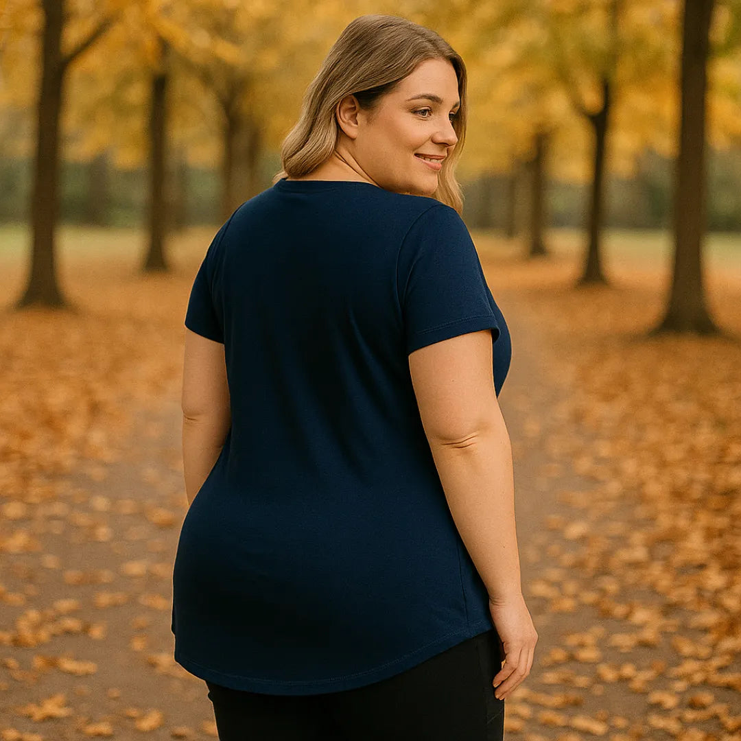 Camiseta azul marinho bĂĄsica em modelo plus size em parque com folhas no chĂŁo.