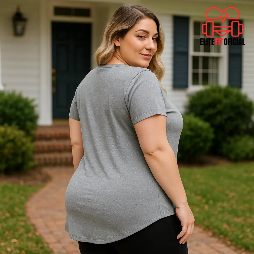 Modelo veste blusa cinza feminina plus size em frente a uma casa.